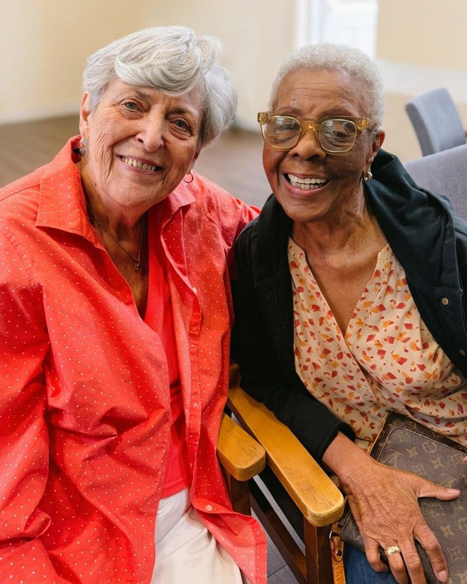 Two Evergreen members sitting together, laughing, in a sunlit room